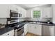 A well-lit kitchen with white cabinets, stainless steel appliances, and a view of the greenery outside the window at 1077 Farmington Rd, Charleston, SC 29412