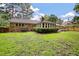 Lush backyard with brick home, screened-in porch, and deck with string lights, creating a serene outdoor space at 109 Lakeview Dr, Summerville, SC 29485