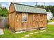 Rustic wooden shed with a green roof and double doors in landscaped yard at 109 Rahway Rd, Goose Creek, SC 29445