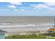 Serene beach view with waves, dunes, and a glimpse of a charming beach house under a partly cloudy sky at 1568 E Ashley Ave, Folly Beach, SC 29439