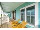 A covered porch featuring wooden deck chairs, windows, and the entry door at 1568 E Ashley Ave, Folly Beach, SC 29439
