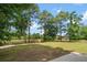 Large backyard featuring a wooden fence, mature trees, and partial views of a pond for a serene outdoor space at 1578 Stanwick Dr, Johns Island, SC 29455