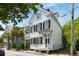 Charming two-story white home featuring a double porch, black shutters, and classic architecture, surrounded by lush greenery at 16 Trumbo St, Charleston, SC 29401