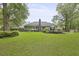 Expansive backyard featuring lush green grass, mature trees, a stone chimney, and a wooden deck at 189 Fox Chase Dr, Goose Creek, SC 29445