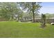 Expansive backyard featuring lush green grass, mature trees, a stone chimney, and a wooden deck at 189 Fox Chase Dr, Goose Creek, SC 29445
