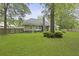 Expansive backyard featuring lush green grass, mature trees, a stone chimney, and a wooden deck at 189 Fox Chase Dr, Goose Creek, SC 29445