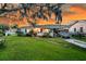 Charming single-story home with beautiful landscaping and a spacious front yard at sunset at 200 Wappoo Rd, Charleston, SC 29407
