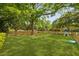 Expansive backyard featuring lush green grass, mature trees, swing, playhouse, and picket fence at 2060 Wappoo Hall Rd, Charleston, SC 29412