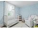Charming Bedroom features light blue wallpaper, white crib, rocking horse, and comfortable chair at 2060 Wappoo Hall Rd, Charleston, SC 29412