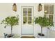 Close-up of a welcoming front door, flanked by potted plants and stylish lanterns at 2060 Wappoo Hall Rd, Charleston, SC 29412