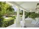 Relaxing front porch with white columns, hanging ferns, and comfortable seating overlooking the manicured lawn at 2060 Wappoo Hall Rd, Charleston, SC 29412