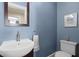 Traditional powder room features blue walls, a pedestal sink, dark framed mirror and toilet at 2060 Wappoo Hall Rd, Charleston, SC 29412