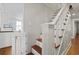 Classic wooden staircase featuring white banisters and a view to the kitchen at 2060 Wappoo Hall Rd, Charleston, SC 29412