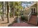 Back patio with red steps leading to the backyard and lake with a brick patio and greenery at 2105 Loblolly Ln, Seabrook Island, SC 29455