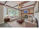 Inviting living room with exposed wood beam ceiling, brick fireplace, and bay windows overlooking the yard at 2340 Ashley River Rd, Charleston, SC 29414