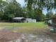 Spacious backyard with a metal carport, storage shed and gardening beds, surrounded by lush green trees and grass at 277 Carolina Cir, Walterboro, SC 29488