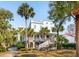 Elegant light blue two-story home featuring a spacious front porch and staircase, enhanced by lush palm tree landscaping at 3 Cross Ln, Isle of Palms, SC 29451