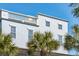 Close-up of a three-story home featuring classic architecture with white balconies and lush palm tree surroundings at 3 Cross Ln, Isle of Palms, SC 29451