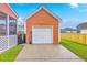 A detached orange garage with white door, concrete driveway and green grass in the back yard at 309 Harriswood Ln, Moncks Corner, SC 29461