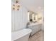 Elegant bathroom featuring a soaking tub, double sinks, decorative lighting, and wooden-look tile floor at 37 Fort Royal Ave, Charleston, SC 29407