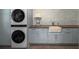 Modern laundry room with stacked washer/dryer, shaker cabinets, and decorative wallpaper at 37 Fort Royal Ave, Charleston, SC 29407