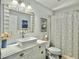 Bright bathroom featuring a vessel sink atop a distressed vanity and decorative mirror with tiled shower at 482 Planters Trace Dr, Charleston, SC 29412