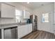 Well-lit kitchen boasts stainless steel appliances, granite counters, white cabinets, and wood-look flooring at 576 Polaris Way, Summerville, SC 29486