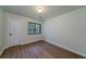 The empty bedroom boasts sleek, hard flooring, neutral paint, bright window, and paneled door at 103 Four Iron Dr, Summerville, SC 29483