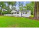 A cozy, one-story home with green lawn, front porch, and surrounded by lush trees at 106 N Pine St, Summerville, SC 29483