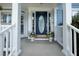 A close-up of the entryway featuring a blue oval door framed by white columns and seasonal potted plants at 1250 White Tail Path, Charleston, SC 29414
