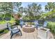 Backyard patio area features a stone fire pit encircled by four blue Adirondack chairs and bordered by lush greenery and plantings at 134 Etiwan Park St, Charleston, SC 29492