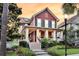 Inviting two-story home featuring a welcoming front porch, white columns, dark shutters, and lush landscaping at 134 Etiwan Park St, Charleston, SC 29492