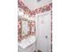 Bathroom featuring a patterned wallpaper, white sink, and gold fixtures at 202 Fishburne St, Charleston, SC 29403
