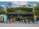 Charming exterior of Three Little Birds cafe covered in lush greenery with outdoor seating at 22 Charlestowne Rd, Charleston, SC 29407