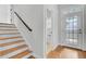 Staircase with wooden treads, white risers, and dark wood railing, and bright foyer with windowed front door at 2516 Willbrook Ln, Mount Pleasant, SC 29466