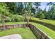 Landscaped backyard featuring a pond, palm trees, green lawn, and wood fence at 348 Spindlewood Way, Charleston, SC 29414