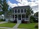 Charming two-story home featuring a cozy front porch, complemented by palm trees and lush green lawn at 3739 Goodwater St, Mount Pleasant, SC 29466
