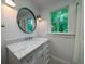 Bathroom with wainscoting, marble countertop, white vanity, and round mirror at 375 Seewee Cir, Mount Pleasant, SC 29464