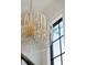 Modern chandelier with custom detail, close up, next to a large window with black frame at 3871 Sawyers Island Dr, Mount Pleasant, SC 29466