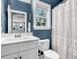 Blue bathroom features a white vanity, toilet and a shower/tub with a floral shower curtain at 3873 Hanoverian Dr, Mount Pleasant, SC 29429