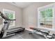 Bright exercise room featuring a treadmill, weight bench, rubber flooring, and natural light from two windows at 3873 Hanoverian Dr, Mount Pleasant, SC 29429