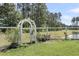 Serene backyard with white picket fence, garden gate, and pond, perfect for relaxation and enjoying nature at 404 Bowstring Dr, Huger, SC 29450