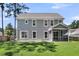 Wide shot of the expansive backyard with lush green grass, a screened porch, and mature trees at 404 Bowstring Dr, Huger, SC 29450