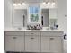 Bright bathroom with double sinks, a neutral cabinet, a mirror, and view to the blue sky at 404 Bowstring Dr, Huger, SC 29450