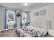 Bright bedroom featuring two sunny windows with blue curtains and a queen-size bed with floral bedding at 404 Bowstring Dr, Huger, SC 29450