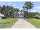 Charming two-story home with a well-manicured lawn and long driveway leading to the garage at 404 Bowstring Dr, Huger, SC 29450