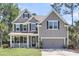 Inviting two-story home with a cozy front porch, black shutters, and beautiful lawn at 404 Bowstring Dr, Huger, SC 29450