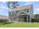 Gray two-story home with a screened-in porch, surrounded by a green lawn and trees, offers a tranquil outdoor living space at 404 Bowstring Dr, Huger, SC 29450