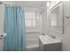 A well-lit bathroom with a shower-tub combination, a light-blue shower curtain, and a light-gray vanity at 407 Raysor St, Saint George, SC 29477