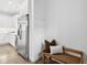 Hallway view with stainless steel refrigerator and a cushioned bench with pillows leading into a modern, all-white kitchen at 42 Poinsett St # B, Charleston, SC 29403